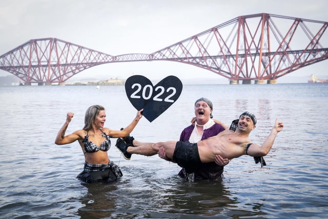 Joda Quigley, from Falkirk holds up a 2022 love heart as she takes part with others in a New Year's Day dip in front of the Forth Bridge at South Queensferry, Edinburgh. Covid restrictions across Scotland have meant that many new year traditions including the official annual Loony Dook have been cancelled. Picture date: Saturday January 1, 2022. PA Photo. Photo credit: Jane Barlow/PA Wire