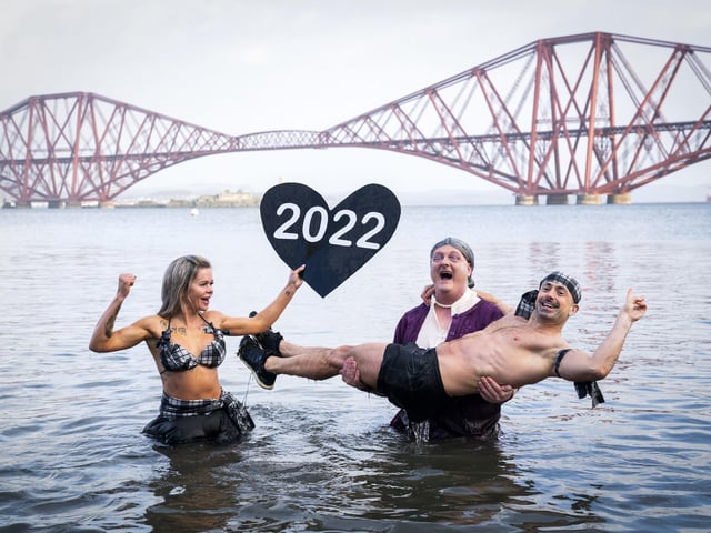 Joda Quigley, from Falkirk holds up a 2022 love heart as she takes part with others in a New Year's Day dip in front of the Forth Bridge at South Queensferry, Edinburgh. Covid restrictions across Scotland have meant that many new year traditions including the official annual Loony Dook have been cancelled. Picture date: Saturday January 1, 2022. PA Photo. Photo credit: Jane Barlow/PA Wire