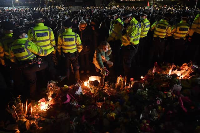 A well-wisher places a adds a tribute to the growing pile from a gap in a police cordon (Photo by JUSTIN TALLIS / AFP) (Photo by JUSTIN TALLIS/AFP via Getty Images)