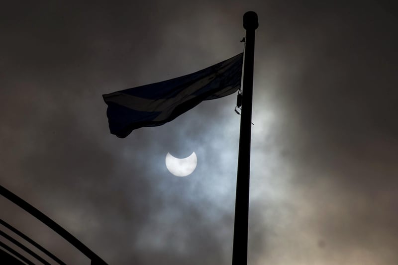 Experts advised looking safely at the sun just after 11am in order to see the eclipse at its peak. Here is another shot of it from Princes Street gardens in Edinburgh as a Saltire flies below it.