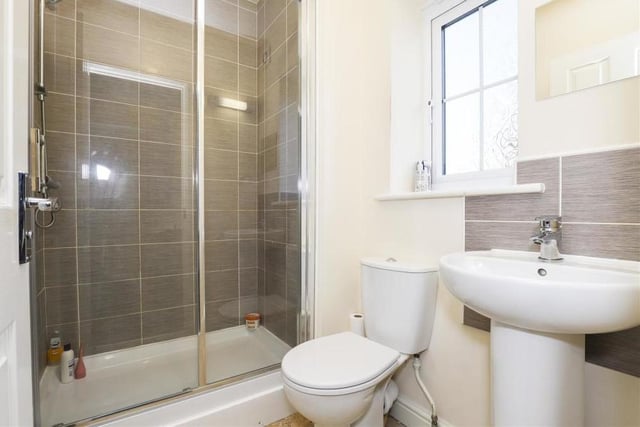 The en suite to the master bedroom features a shower enclosure with a wall-mounted shower, a low-level flush WC and a pedestal wash basin. The floor is tiled, as are some of the walls, while there is also a wall-mounted radiator, an extractor fan and a uPVC double-glazed, opaque window to the back.