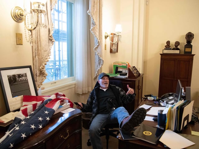 A supporter of US President Donald Trump sits inside the office of US Speaker of the House Nancy Pelosi as he protest inside the US Capitol in Washington, DC, January 6, 2021. - Demonstrators breeched security and entered the Capitol as Congress debated the a 2020 presidential election Electoral Vote Certification. (Photo by SAUL LOEB / AFP)