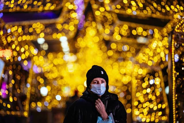 A woman wearing a face mask walks under decorations and lights set up for the upcoming Christmas and New Year celebrations (Photo by DIMITAR DILKOFF/AFP via Getty Images)