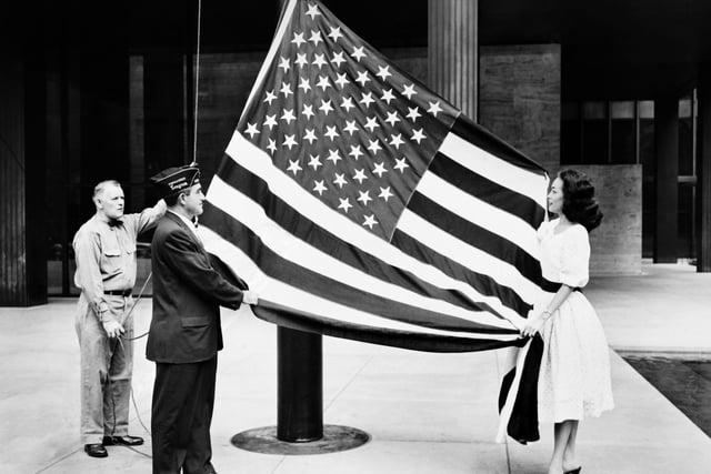 Hawaii became the 50th US state. An officer hoists the new United States flag decorated with its 50 stars during a presentation ceremony at the American Legion headquarters on August 21, 1959 in New York.