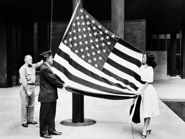 Hawaii became the 50th US state. An officer hoists the new United States flag decorated with its 50 stars during a presentation ceremony at the American Legion headquarters on August 21, 1959 in New York.