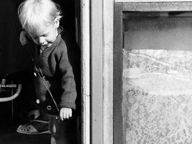 Young girl points an elastic band at a passing cat, Edinburgh, 1960s.