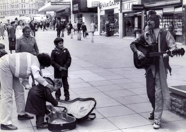 Pictured in action in Fargate complete with cap, bells and guitar, is busking jester, Roger Pugh. In the background you can see the long gone Wimpy Bar, Peter Lord's shoe shop, and Ratner's jewellers, October 1983