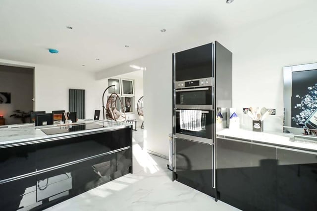 The recently fitted kitchen comprises base and wall units in a high gloss finish with central island with induction hob and downdraft extractor, integrated double oven, and feature sink and drainer.
