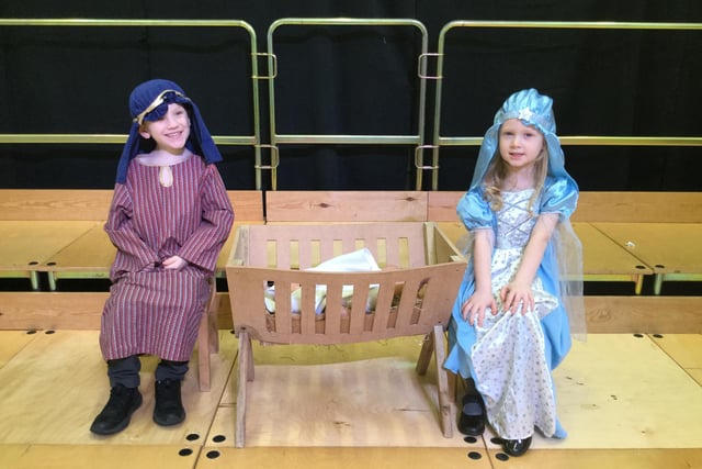 Schoolchildren rehearsing for their roles as Mary and Joseph in the Christmas play with baby Jesus in the manger between them