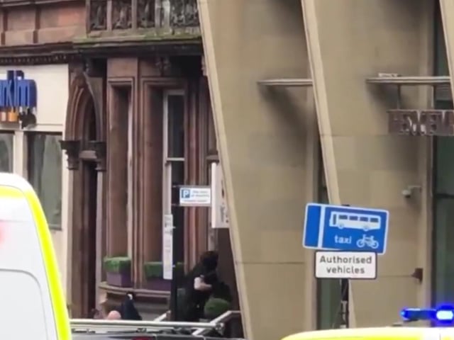 Armed police pictured entering a building in West George Street as residents are evacuated