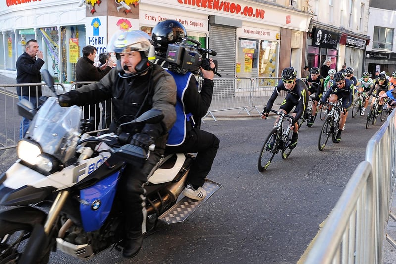 The cyclists follow the lead motorcycle and cameraman as they pass the familiar sight of the late Dennis Alexander' Chickenshop premises (Pic: Neil Doig/Fife Free Press)