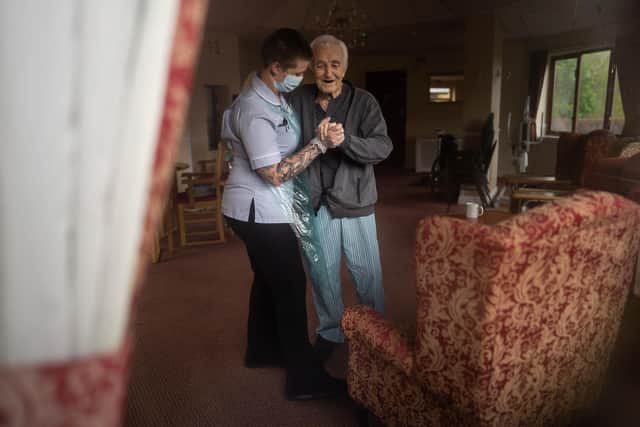 Jack Dodsley, 79, with a carer in full PPE at Newfield Nursing Home, Sheffield, April 2020. Eleven residents at the 60 bed home have died from coronavirus and the company which runs this and two otrher care homes has 36 staff who have also tested positive and another 31 who are self-isolating. See SWNS story SWLEcare.  These moving behind-the-scenes photos reveal a rare glimpse of day-to-day life inside a care home devastated by coronavirus.  The images give the clearest look yet at how dedicated key workers are tirelessly caring for some of the most vulnerable people in British society. They emerge the day after the government finally announced that all care home residents and staff in England will be able to access tests, regardless of whether they have symptoms. Latest figures revealed a third of all coronavirus deaths are now happening in care homes, with a grim figure of 2,000 given for the week ending April 17.
