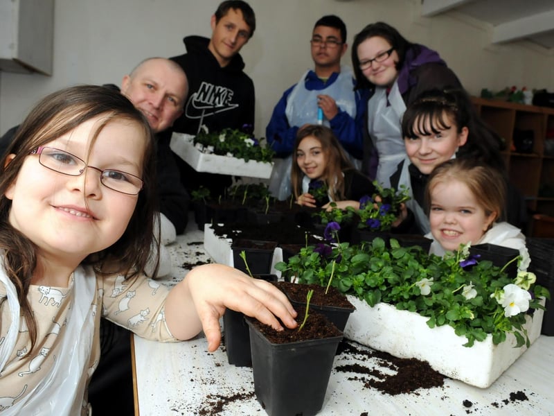 What a great project! This scene comes from 2013 and shows youngsters at the Holder House Garden Project Saturday Club planting flowers. Is there someone you know in the photo?