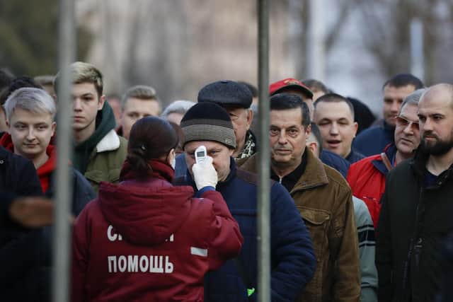 A medical worker checks the temperatures of soccer fans, for coronavirus symptoms, as they line-up to enter a stadium during the Belarus Championship soccer match between Gorodeya and Shakhter in the town of Gorodeya, Belarus: AP Photo/Sergei Grits