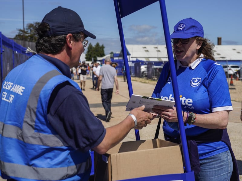 Portsmouth fan grabs a program as supporters return to Fratton Park.