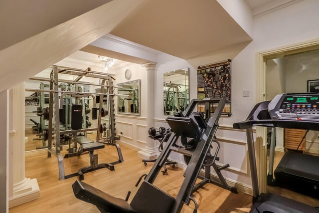 The home gymnasium boasts wood effect flooring and decorative wall pillars, and provides plenty of room for several pieces of equipment.