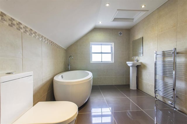 The fully tiled bathroom has a contemporary suite including a corner shower and oval freestanding bath with floor mounted mixer tap.