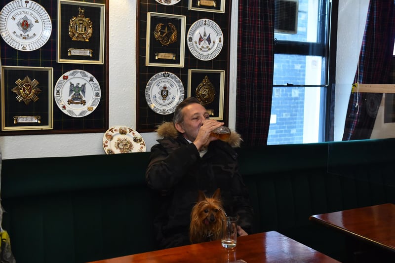 A man  enjoys a drink with a dog at The Swan Inn pub. (Photo by Nathan Stirk/Getty Images)