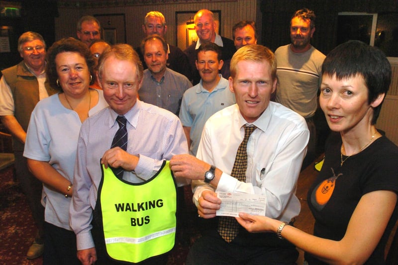 Sheffield Driving Schools Association present a cheque  for £2,000 to the Walking Buses association at Davy Social Club, Prince of Wales Road in October 2004. Pictured left to right are association president George Beal, Sheffield Road Safety Officer Mike Stanley and association secretary Karen Bannister, surrounded by association members