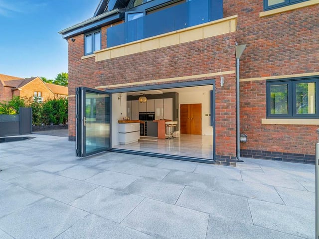 A photo that shows how the kitchen, diner and family area leads out on to an extensive patio space. Truly open plan!