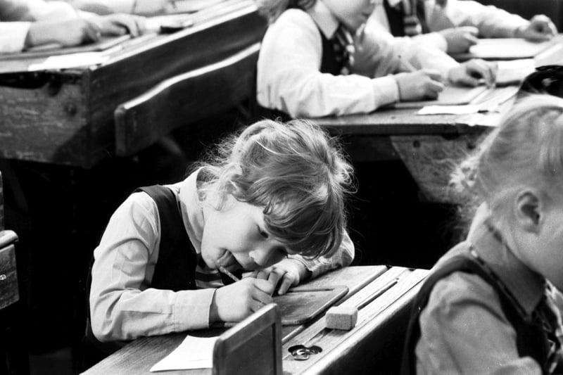 Children from Leith Primary School at McDonald Road library as part of Local History Week, September 1988. A little girl, tongue sticking out, tries writing with a slate and pencil.