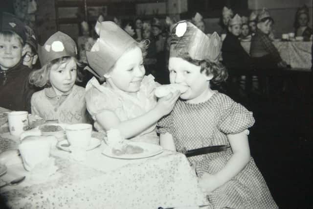 Two youngsters share a cake at a school Christmas party in the 1950s