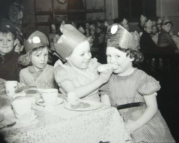 Two youngsters share a cake at a school Christmas party in the 1950s