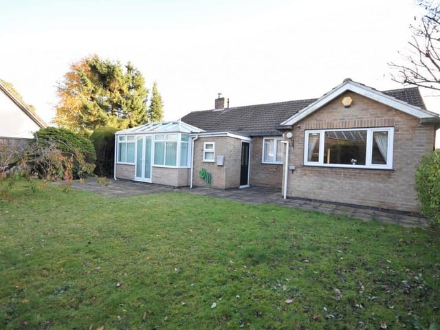 Let's take a look outside now, beginning with this view of the bungalow from the rear. The lawned garden is well enclosed by hedges and fences.