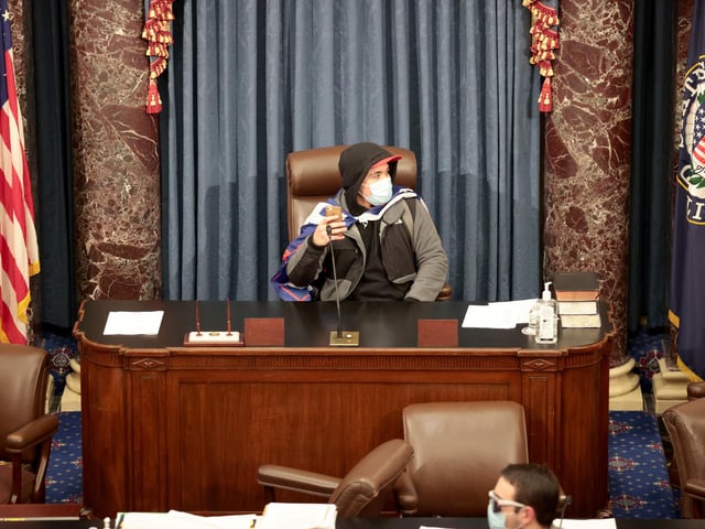 A protester sits in the Senate Chamber on January 06, 2021 in Washington, DC. Congress held a joint session today to ratify President-elect Joe Biden's 306-232 Electoral College win over President Donald Trump. Pro-Trump protesters have entered the U.S. Capitol building after mass demonstrations in the nation's capital. (Photo by Win McNamee/Getty Images)