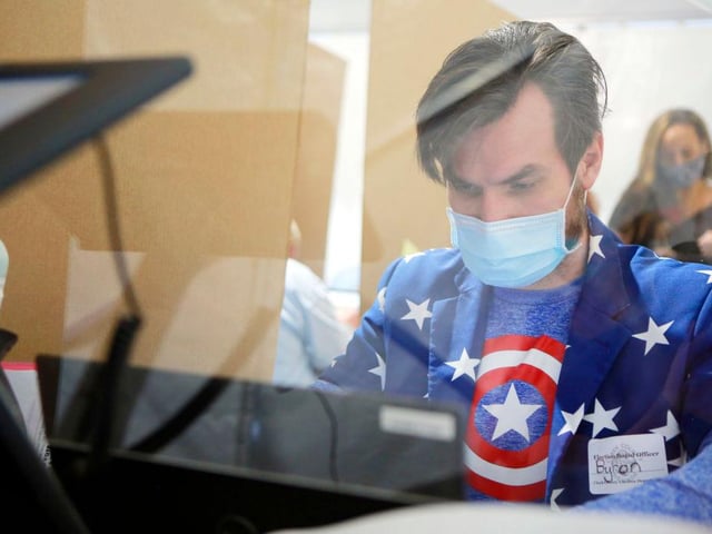 Poll worker Byron Rae works behind protective plexiglass on Election Day at downtown Summerlin in Las Vegas, Nevada.