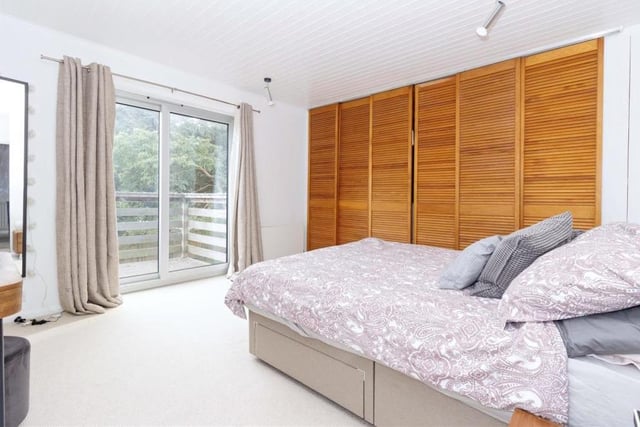 Stunning features of the Littlehampton property include floor-to-ceiling windows, pine walls and wood-burning stoves. This spacious bedroom features a balcony.