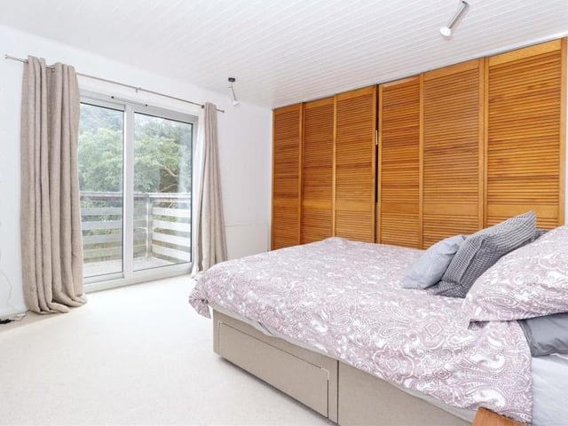 Stunning features of the Littlehampton property include floor-to-ceiling windows, pine walls and wood-burning stoves. This spacious bedroom features a balcony.