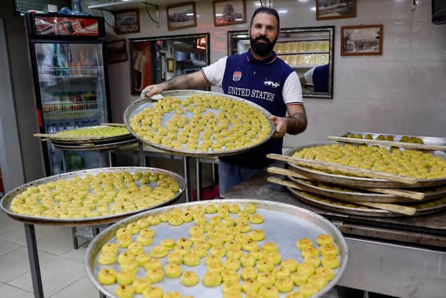 A baker shows trays of traditional date-filled biscuits ahead of Eid al-Fitr, a three-day holiday that marks the end of the Muslim fasting month of Ramadan. (Photo by Ahmad GHARABLI / AFP) (Photo by AHMAD GHARABLI/AFP via Getty Images)