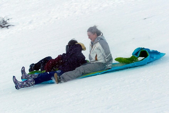 People having fun in a hill-covered in snow in Ringinglow, Sheffield in December 2010, sledging on a plastic sheet