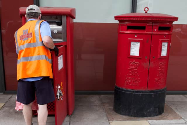 A postman empties a Royal Mail post box        (Photo credit should read ANDREW COWIE/AFP via Getty Images)