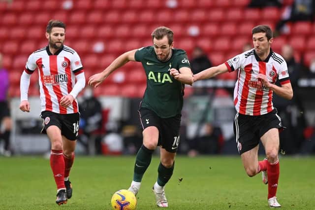 Tottenham Hotspur striker Harry Kane (C) runs with the ball as Sheffield United's Chris Basham (R) and Oliver Norwood (L) chase after him during the Premier League  match at Bramall Lane (Photo by STU FORSTER/POOL/AFP via Getty Images)