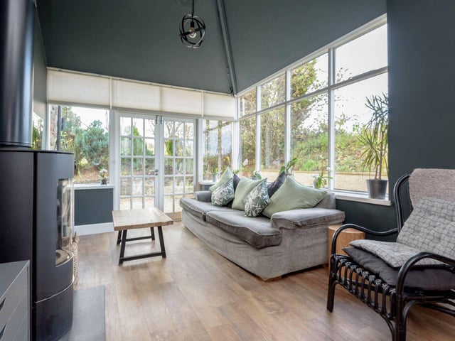 The open-plan kitchen, living and dining room presents flexible space, with French doors and a wood-burning stove