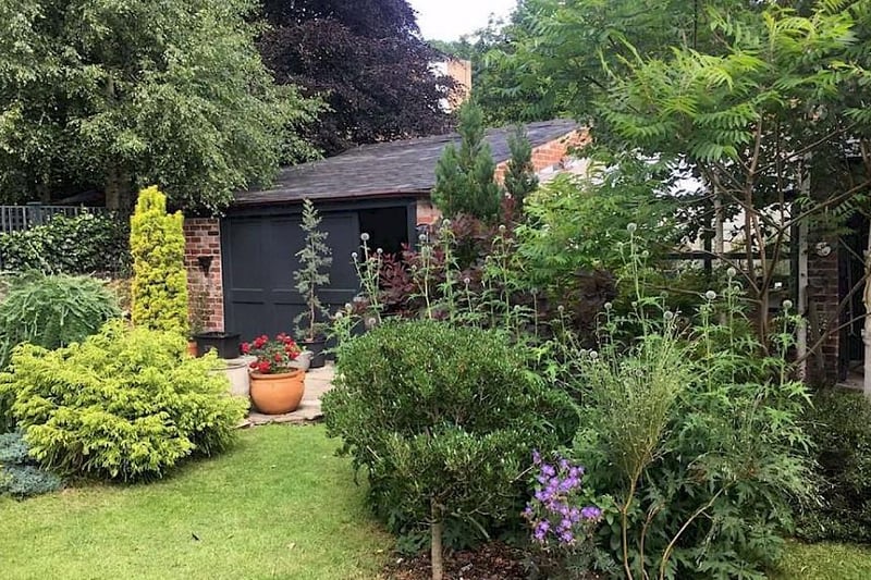 To the rear of the house there is a landscaped garden which includes a decked patio, paved seating area, lawn, planted beds, water feature, a small pond, and various brick-built outbuildings.