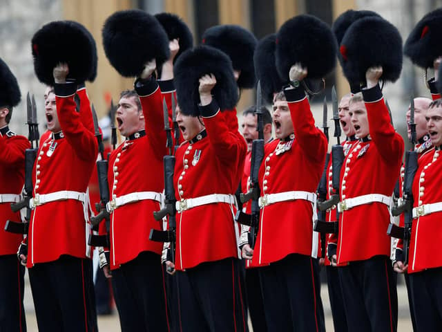 LONDON, ENGLAND - MAY 3: Members of the 1st Battalion and No. 7 Company the Coldstream Guards raise their bearskins as they give three cheers for Queen Elizabeth II after being presented with their new colours Windsor Castle, on May 3, 2012 in Windsor, England. Queen Elizabeth will celebrate her Diamond Jubilee a month from today.  (Photo by Andrew Winning-WPA Pool/Getty Images)