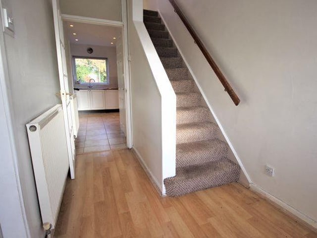 As we prepare to go upstairs, here is the hallway. It boasts laminate flooring, a radiator, decorative ceiling-light and telephone point.