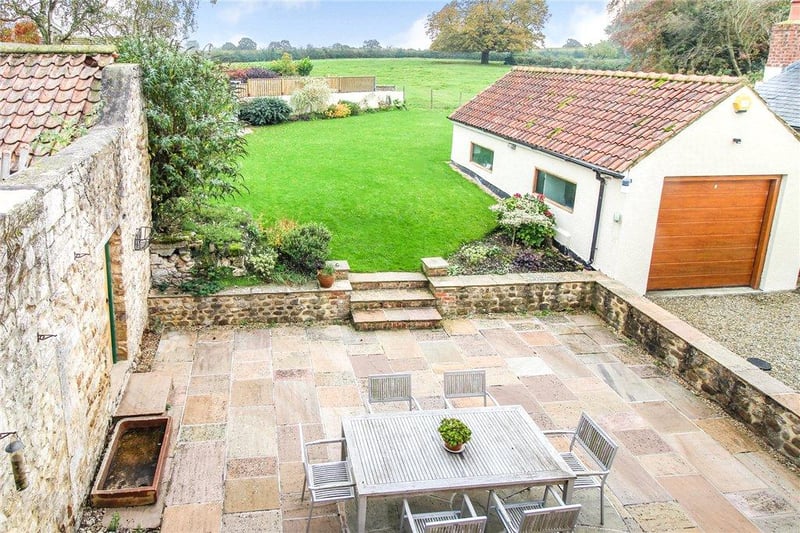 The patio steps lead up to a lawned garden with well stocked shrub borders and an attractive outlook across the rear to adjoining fields
