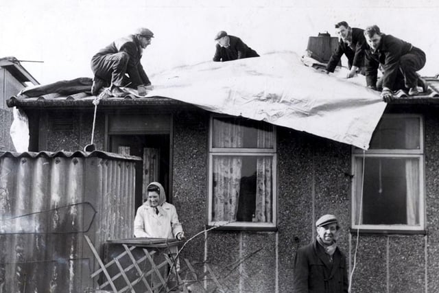 A gale affecting the eastern Pennines wreaked havoc in Sheffield on February 16, 1962, with wind speeds hitting 96mph. Trees were uprooted and over 100,000 buildings were damaged, while four people were killed and 6,000 left without homes. Residents of Skye Edge Avenue are pictured as tarpaulin is laid on February 17.