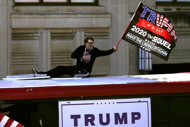 A supporter of President Donald Trump waves a flag from atop a bus outside the Pennsylvania State Capitol. (AP Photo/Julio Cortez)
