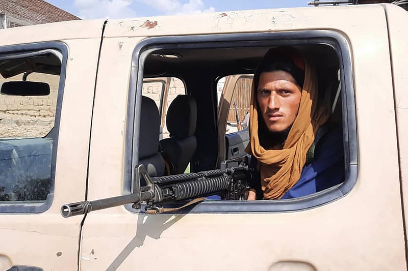 A Taliban fighter sits inside an Afghan National Army (ANA) vehicle along the roadside in Laghman province