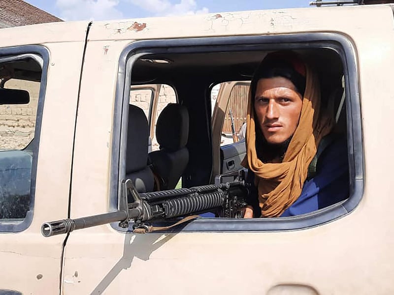 A Taliban fighter sits inside an Afghan National Army (ANA) vehicle along the roadside in Laghman province