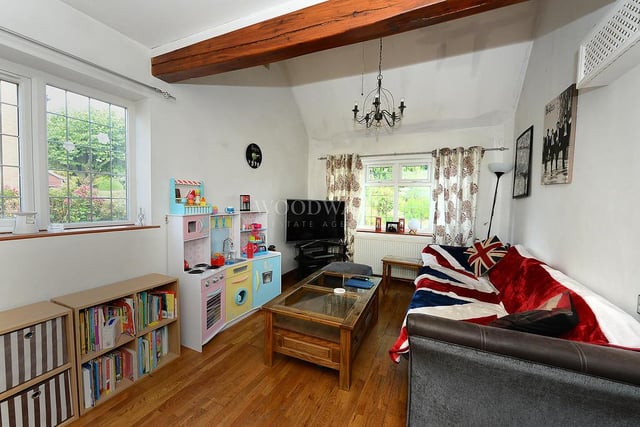 This the snug or family room, which features a multi-fuel burning stove, wood flooring and a concealed boiler unit. There is also a ceiling fan, TV point, radiator, feature tiled wall and double-glazed windows to the front and side of the house.