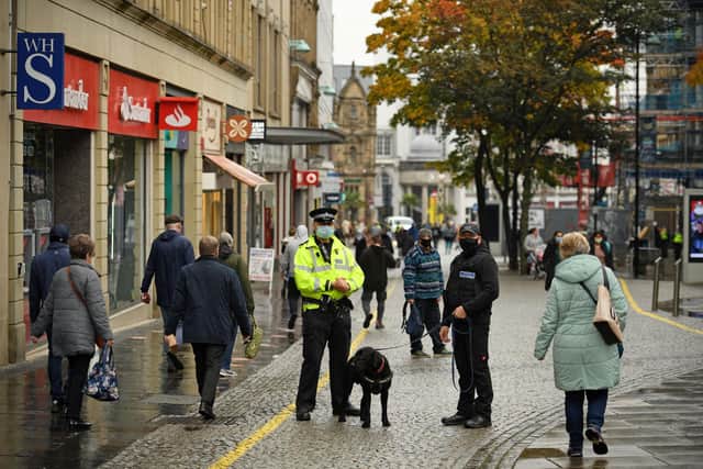 A Police officer speaks with a dog handler in the shopping district in central Sheffield (Photo by OLI SCARFF/AFP via Getty Images)