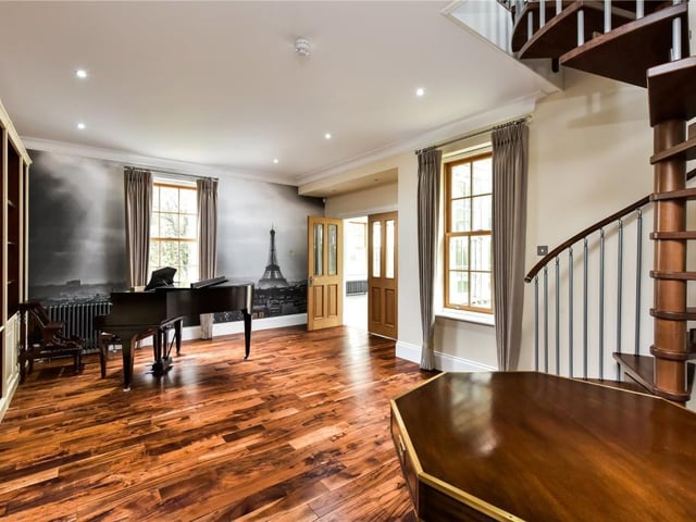 Music room / library with a wall of fitted shelving and doors to conservatory.