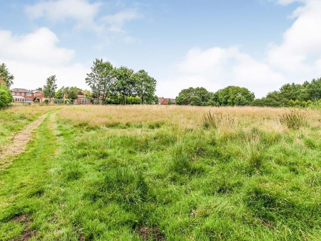 Just a fraction of the two-acre paddock, bordered by a fence and hedges. It features an allotment area, greenhouse and sheds.