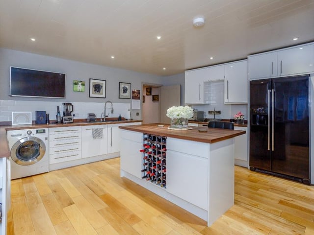 The utility area and back kitchen has a range of units including a large central island and breakfast bar, wooden worktops, modern integrated appliances and an external door.